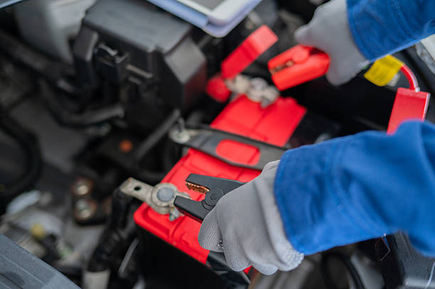 close up hand holding battery charger tools jump start vehicle